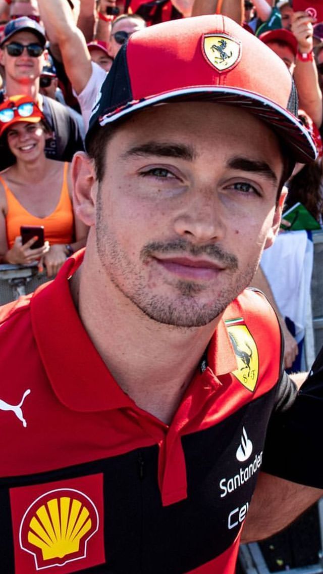 a man in a red shirt and black hat standing next to a group of people