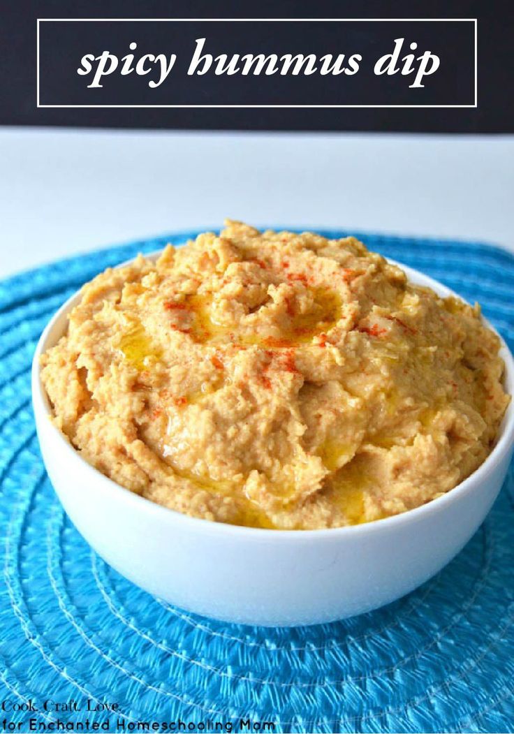 a white bowl filled with hummus dip on top of a blue place mat