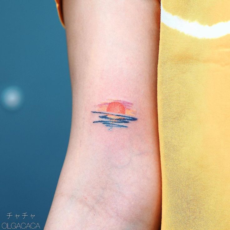 a woman's arm with a sunset tattoo on the left side of her arm