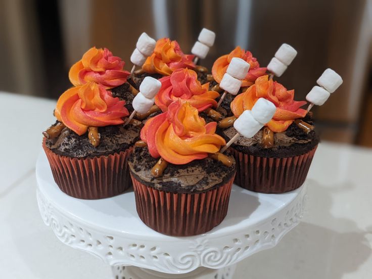 cupcakes decorated with marshmallows and candy on a white cake plate