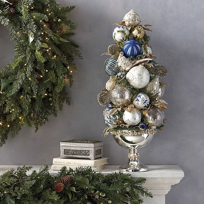 a decorated christmas tree sitting on top of a mantle next to a wreath and books