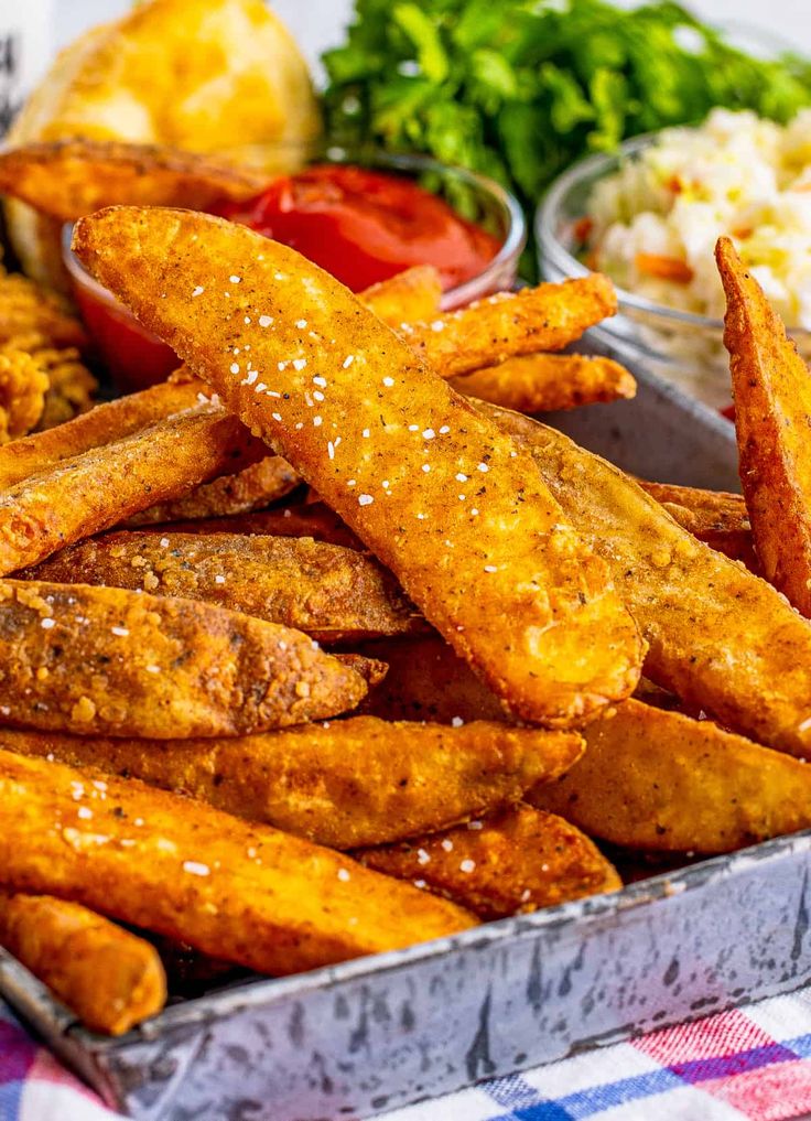 some fried food is on a plate with other foods in bowls and sauces around it