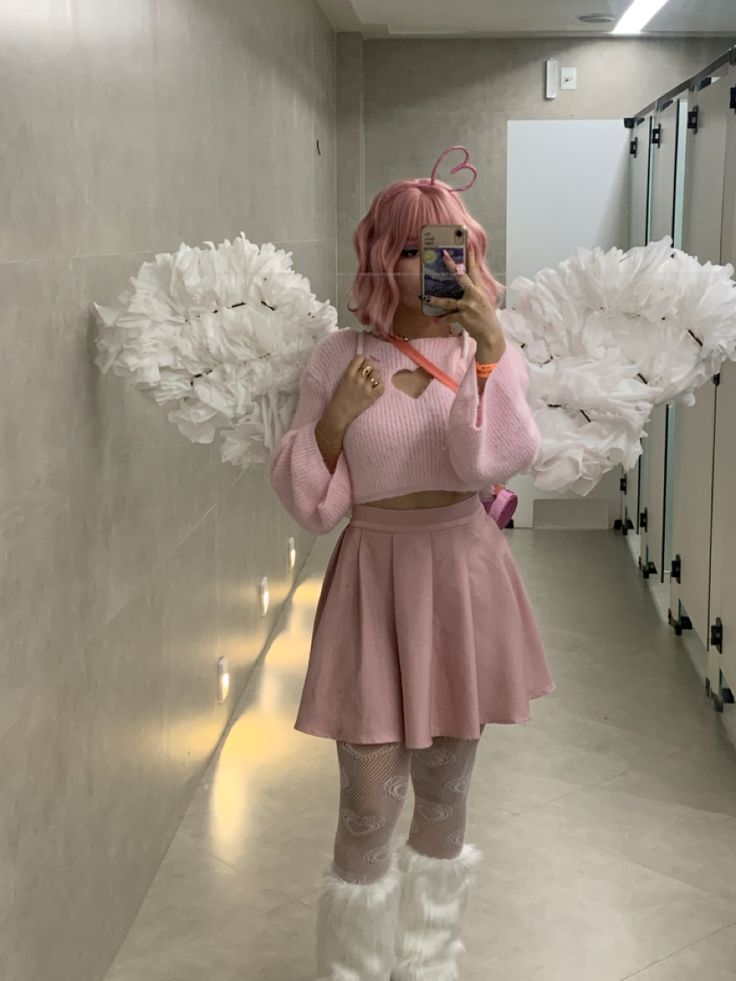 a woman taking a selfie in a bathroom with angel wings on the wall behind her