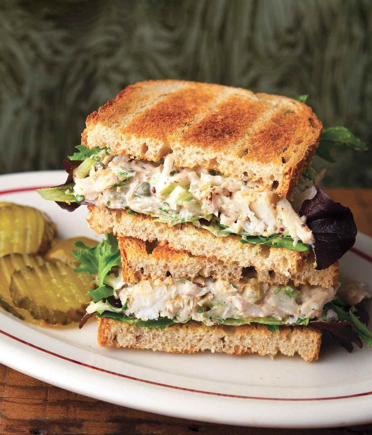 a sandwich cut in half sitting on top of a white plate next to a pickle