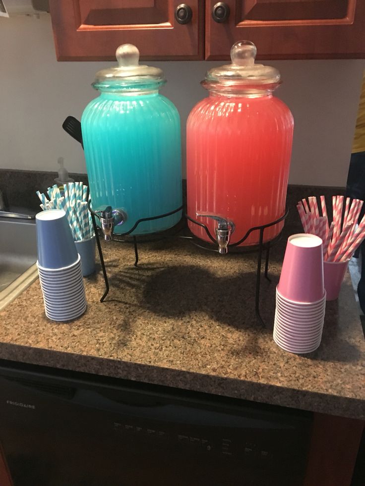 there are two large jars on the counter with toothbrushes in them and one is blue