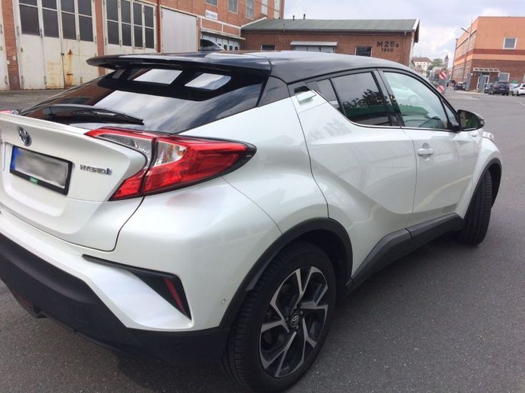 the rear end of a white car parked in a parking lot next to a building