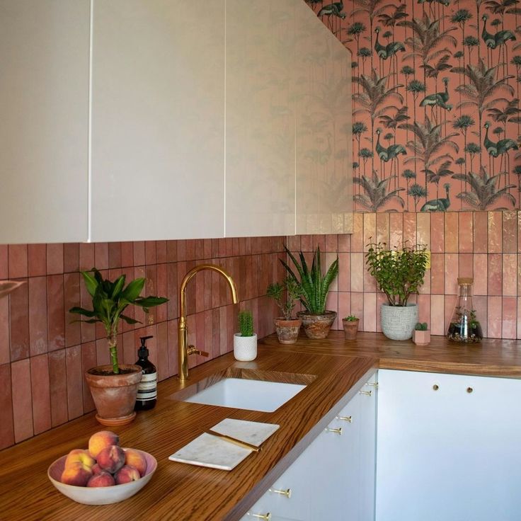 a bowl of fruit sitting on top of a wooden counter next to a kitchen sink