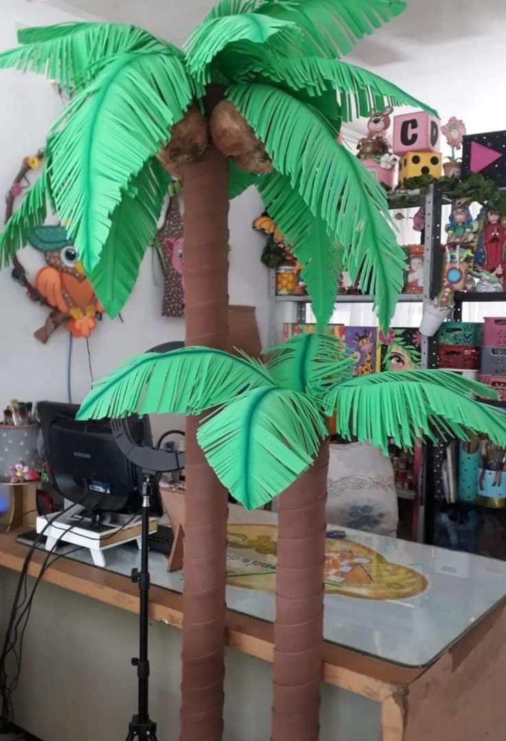 two palm trees sitting on top of a wooden table next to a computer monitor and printer