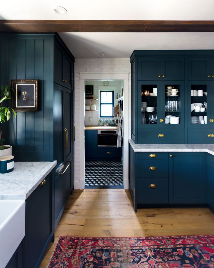 a kitchen with dark blue cabinets and white counter tops, an area rug on the floor