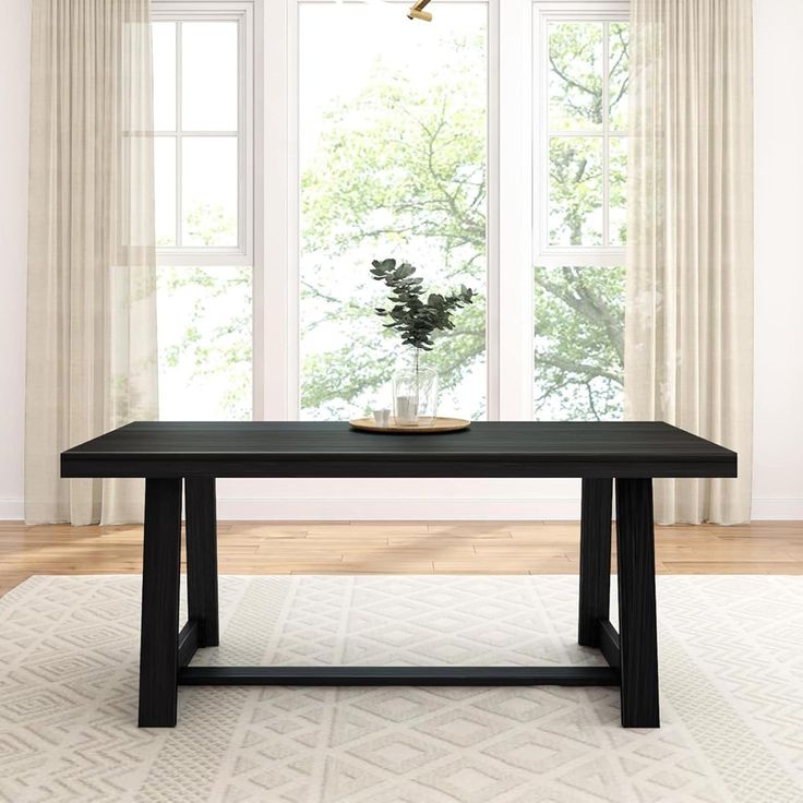 a black table sitting in front of two windows with curtains on either side and a potted plant at the end