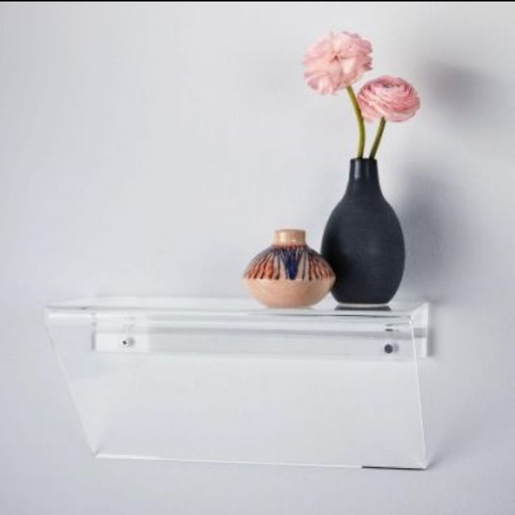 two vases are sitting on a shelf next to each other with flowers in them