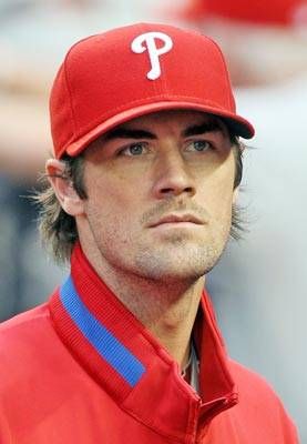 a close up of a baseball player wearing a red hat and blue stripe on his shirt