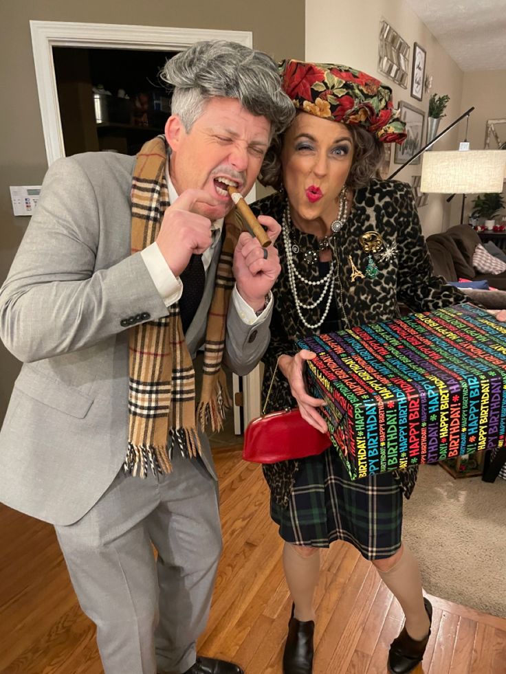 a man and woman dressed up in costume posing for the camera while holding a box