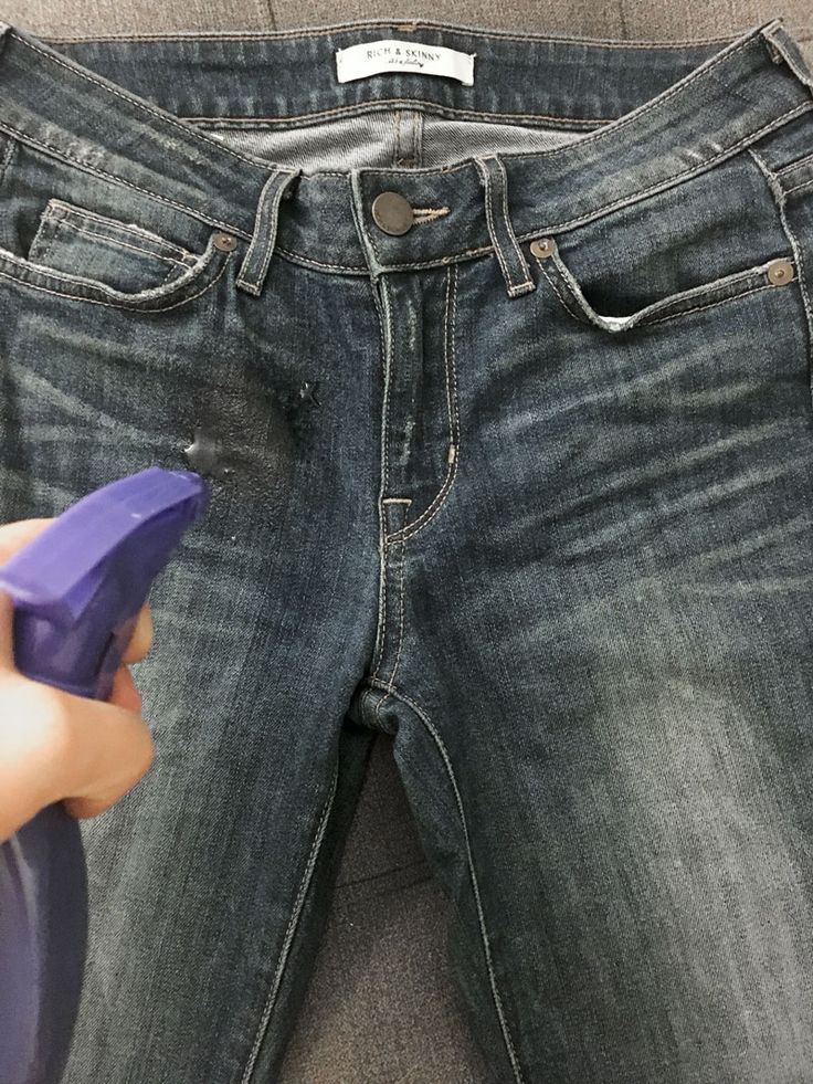 a person holding a purple object in their left hand while standing next to a pair of jeans