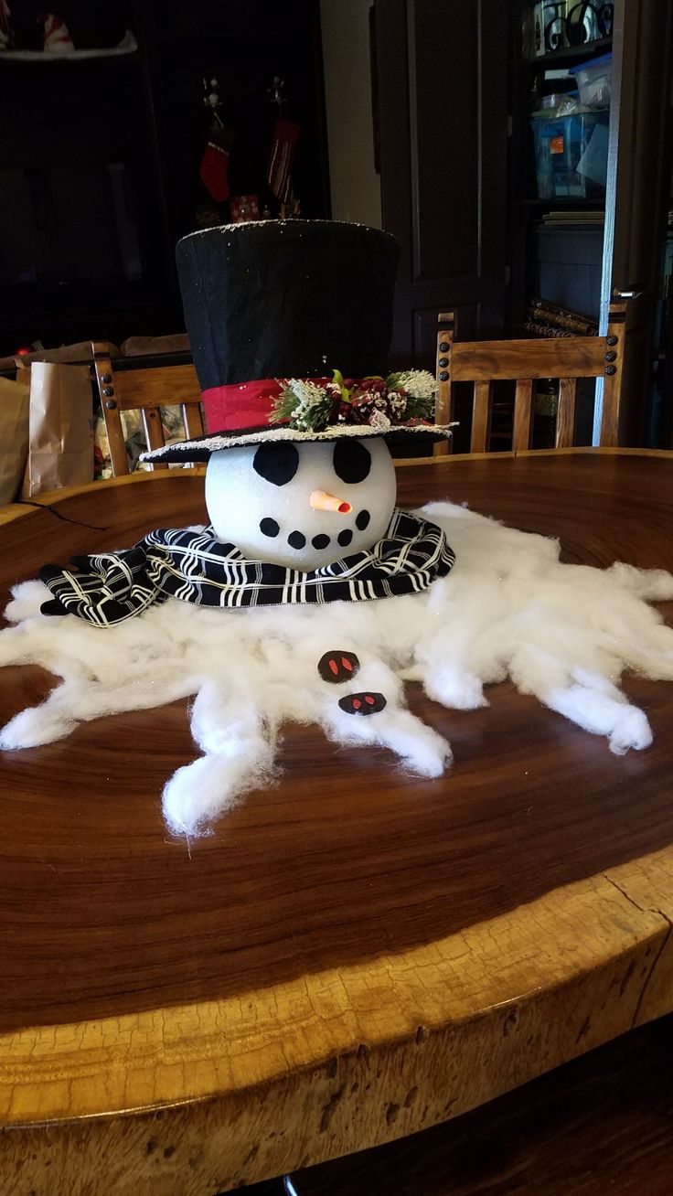 a snowman sitting on top of a wooden table covered in white fluffy furs