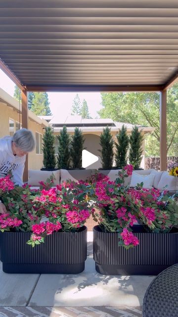 a man is placing flowers in large planters on the patio area outside his home