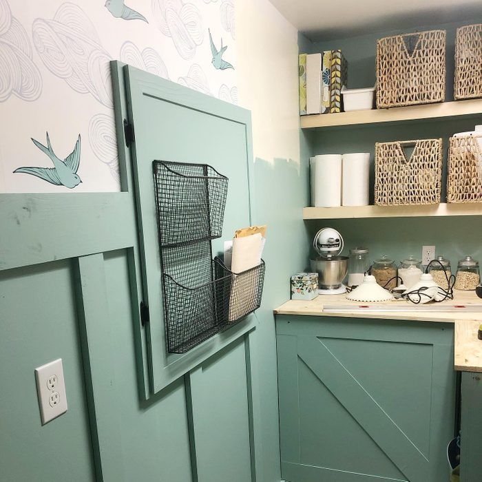 a kitchen with green cupboards and shelves filled with dishes on top of them, next to a sink