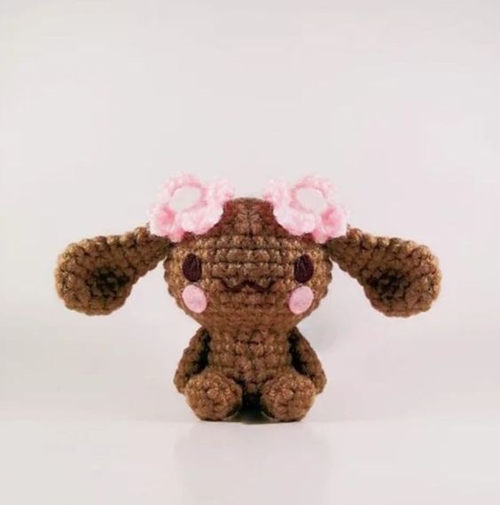 a crocheted stuffed animal with pink flowers on it's head and ears