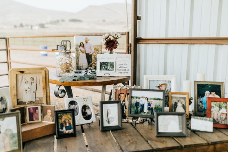 a wooden table topped with lots of pictures and framed photos next to a metal building