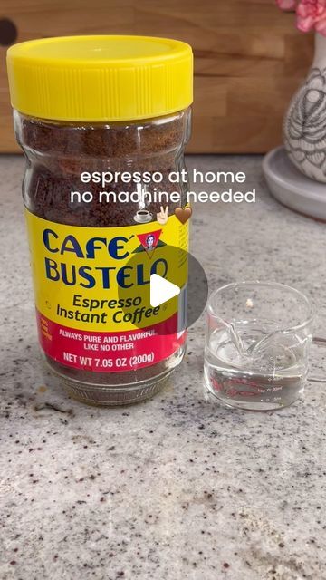 a jar of coffee sits on a counter next to an empty glass cup and saucer