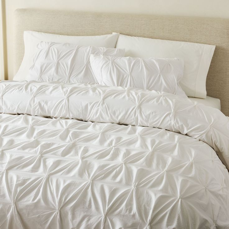 a bed with white sheets and pillows in a bedroom