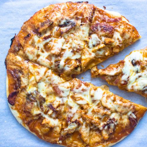 two slices of pizza sitting on top of a blue paper covered tablecloth, with one slice missing from the pizza