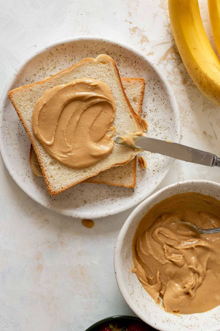 peanut butter spread on toast with bananas in the backgroung and two bowls