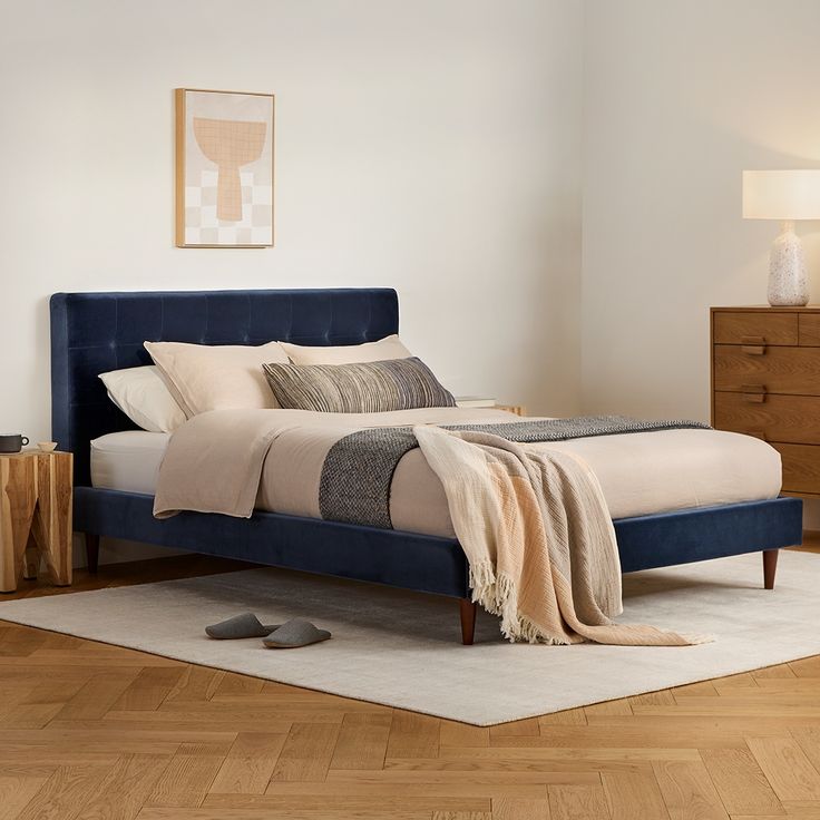 a bed sitting on top of a wooden floor next to a lamp and dressers