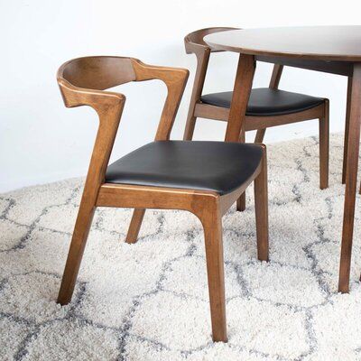 two wooden chairs sitting next to each other on top of a rug