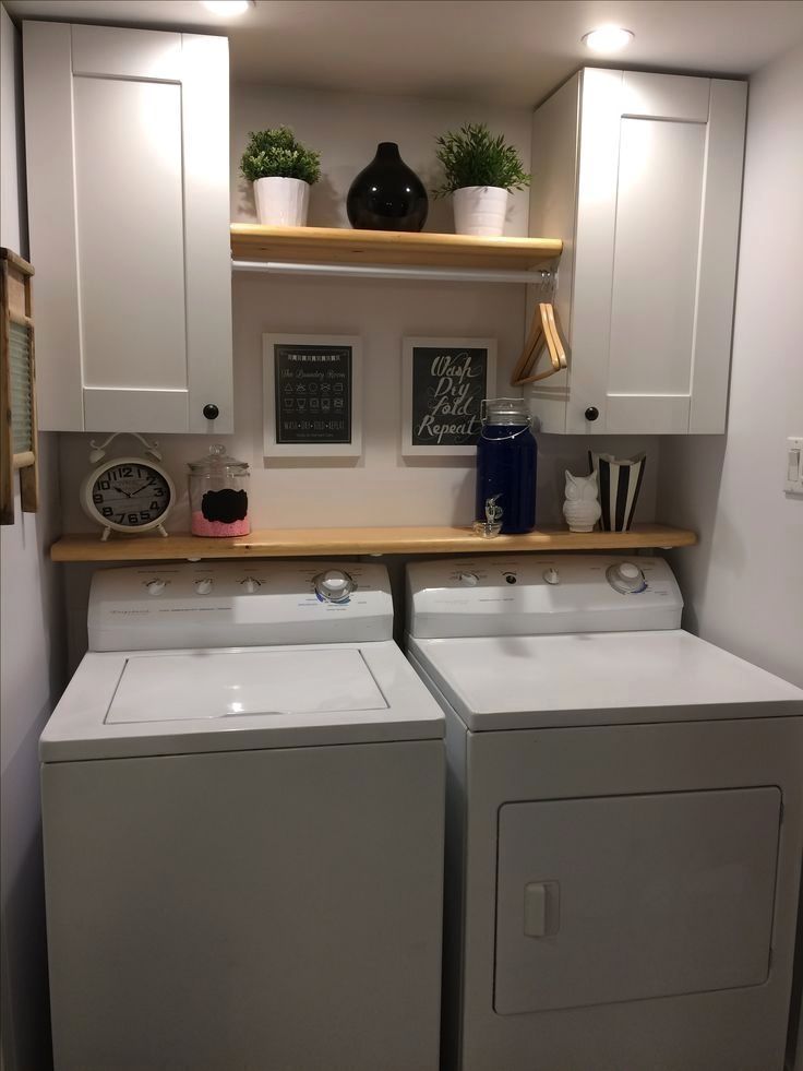 a washer and dryer in a small room with white cupboards on the wall