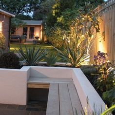 a bench in the middle of a garden with lights shining on it's side