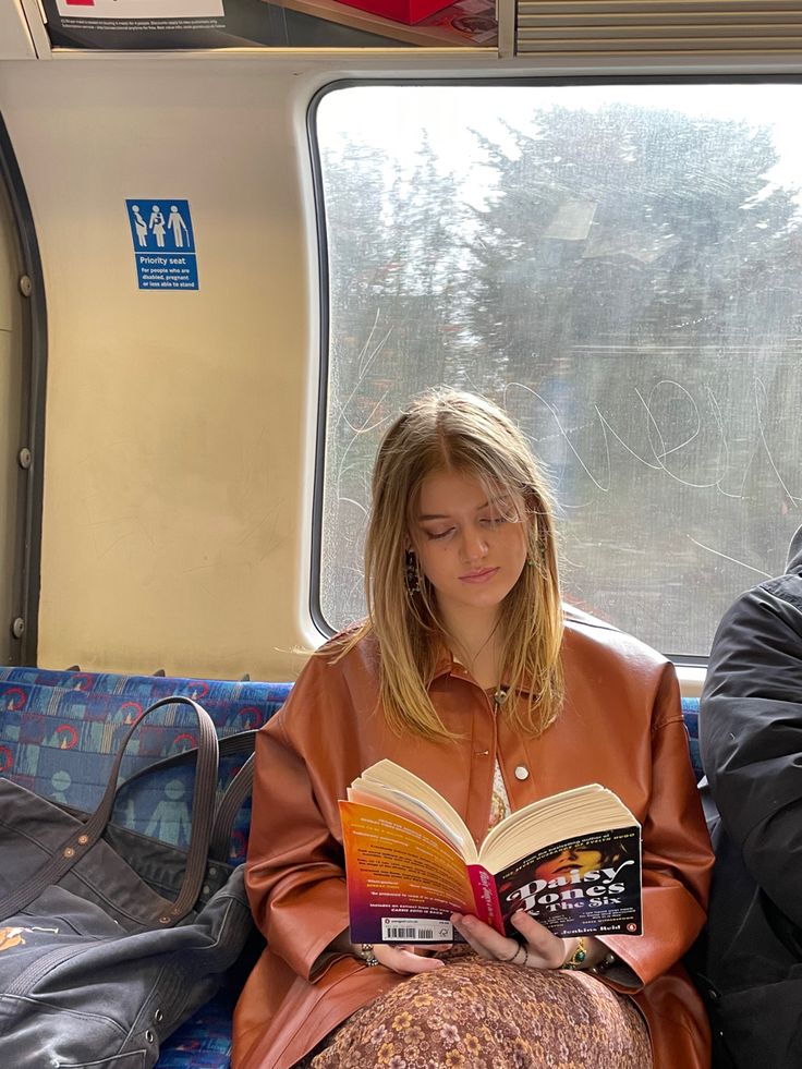 a woman sitting on a train reading a book