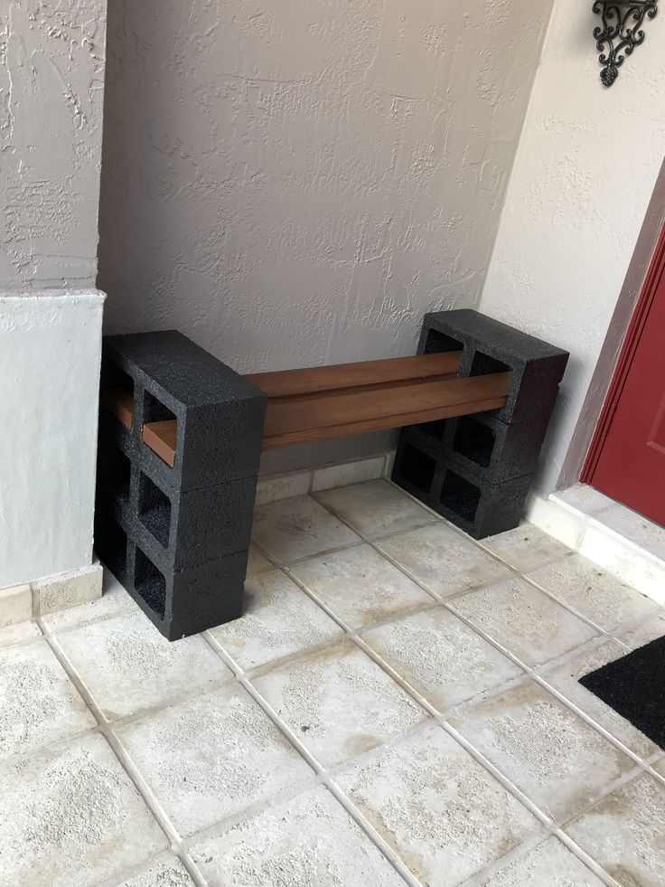 a bench made out of cinder blocks on the floor next to a red front door