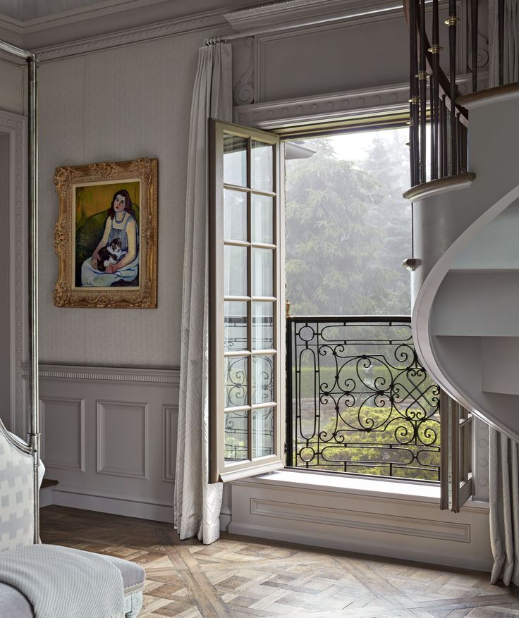 a bedroom with a painting on the wall next to a window and stairs in front of it