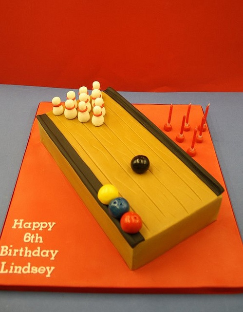 a birthday cake that is shaped like a bowling board with pins and balls on it