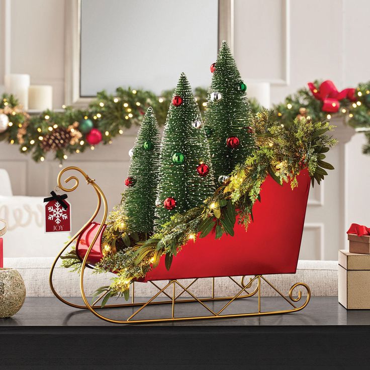 a red sleigh with christmas trees and presents on the table next to it