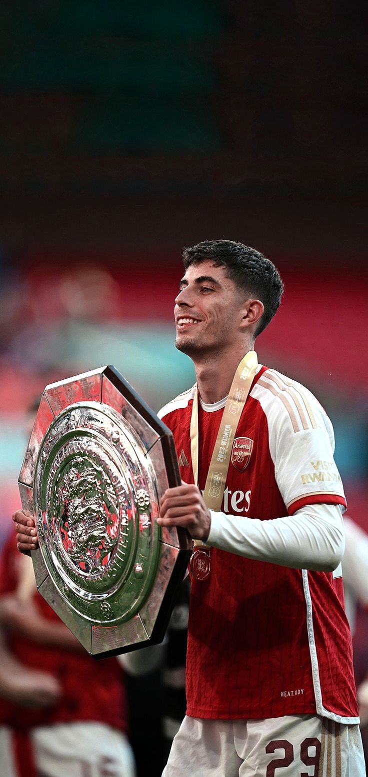 a man holding a silver trophy in his right hand and wearing a red shirt on the other side