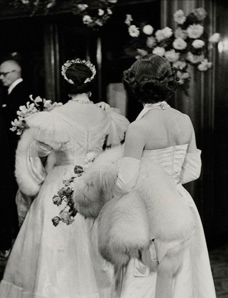 an old black and white photo of two women in wedding dresses walking down the aisle