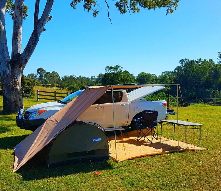 a tent set up in the grass next to two cars