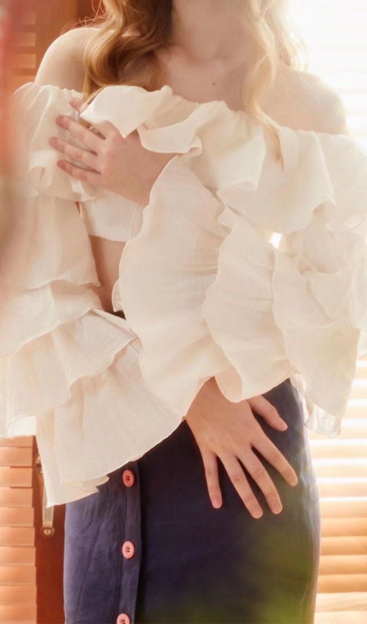 a woman wearing a white top and blue skirt posing for the camera with her hands on her hips