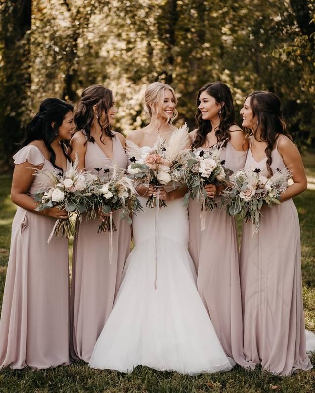 a group of women standing next to each other holding bouquets in their hands and laughing