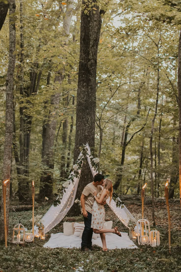 a couple kissing in front of a teepee surrounded by candles