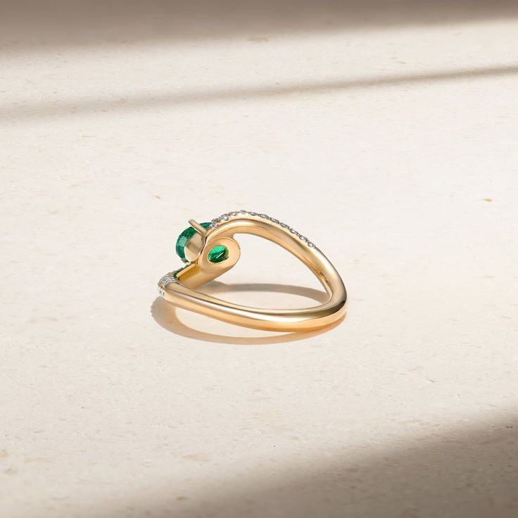 Resting brilliantly at the heart of this daring design is a striking oval shaped emerald that is secured by four claw prongs. Rows of sparkling diamonds embellish the shank as it gracefully spirals towards the center stone in what we consider a new-aged bypass ring. We love our Tempest Ring for the more audacious and in vogue lady. Metal: 18kt Gold Emerald Weight: 0.85 ct. Diamond Weight: 0.50 ct. Measurements: 9.0 mm length *Please note that the listed ct. weights are approximate and may be sub Elegant Emerald Heart Cut Rings, Elegant Emerald Ring With Tension Setting And Round Cut, Elegant Emerald Ring With Tension Setting For May Birthstone, Elegant Formal Heart Cut Emerald Ring, Elegant Emerald Ring In Yellow Gold With Tension Setting, Elegant Emerald Promise Ring With Tension Setting, Elegant Emerald Cut Emerald Ring With Tension Setting, Elegant Tension Setting Ring With May Birthstone, Elegant Heart Cut Emerald Ring