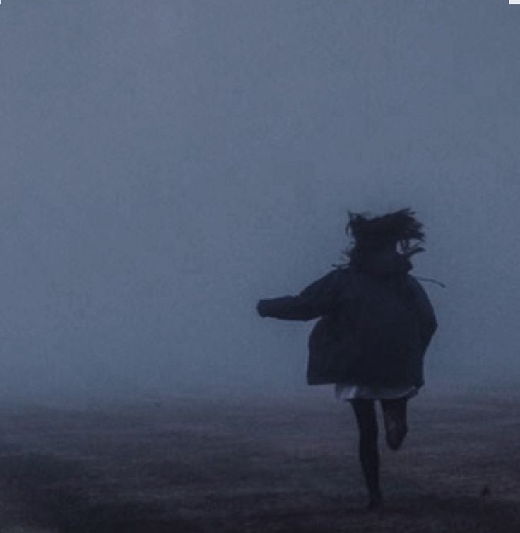 a person running in the fog with an umbrella