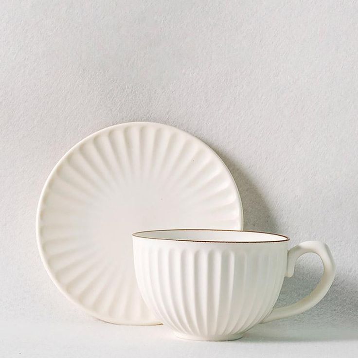 two white cups and saucers sitting next to each other