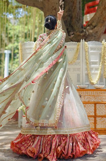 A tulle peshwas, featuring zardoze and resham embroidery, is paired with a salmon pink brocade lehnga and choli. Paired with a mint green organza dupatta accentuated with gota details and tassels. Festival Reception Anarkali Set With Sheer Dupatta, Festival Anarkali Set With Sheer Dupatta For Reception, Pista Green Traditional Wear With Gota Work For Reception, Pista Green Organza Choli With Cutdana, Pista Green Choli With Gota Work In Traditional Drape, Pista Green Raw Silk Sharara With Dupatta, Pista Green Sharara With Sheer Dupatta For Navratri, Pista Green Floor-length Dupatta With Gota Work, Pista Green Traditional Wear With Sheer Dupatta For Navratri