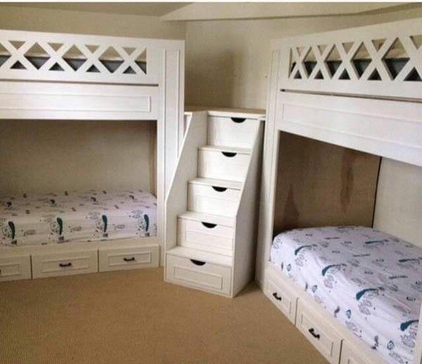 there are two bunk beds with drawers in this room, and one has a stair case