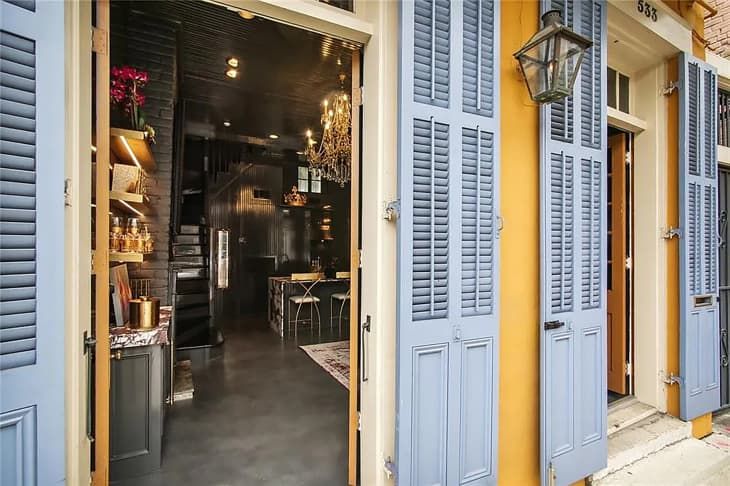 an open door leading into a restaurant with blue shutters and yellow walls on both sides