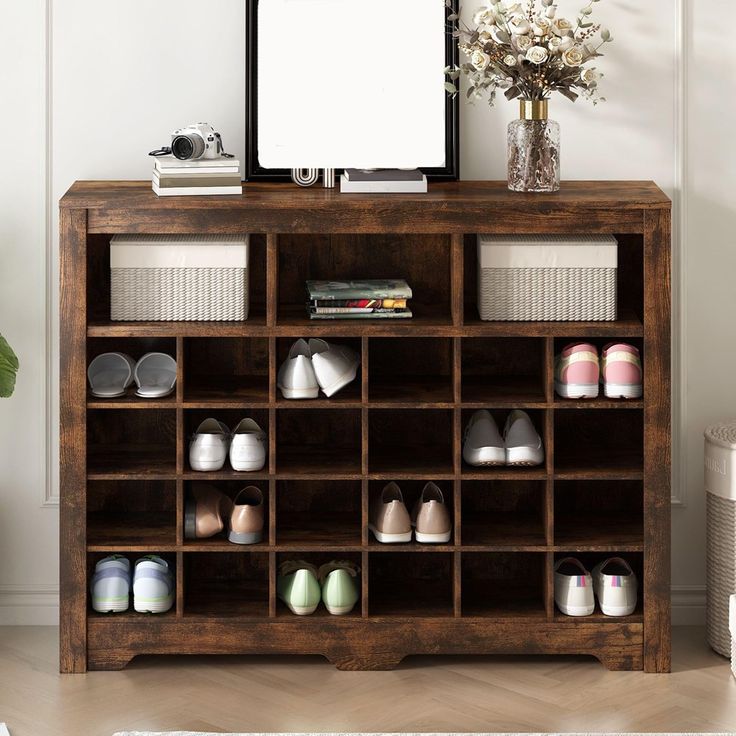 a wooden shelf filled with shoes next to a vase and tv on top of it