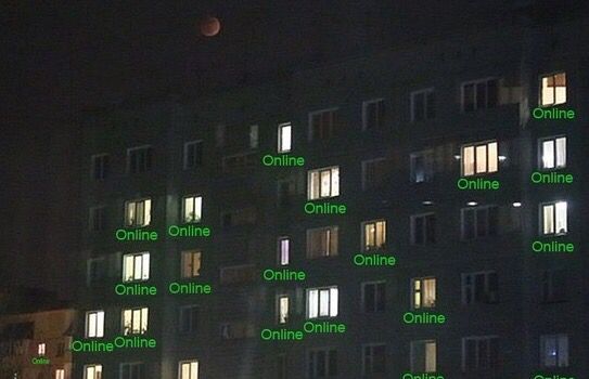 an illuminated building with words written on the windows at night in front of it's moon